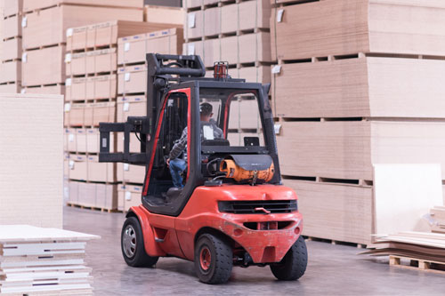 Operario trabajadno en empresa de cartón, con carretilla elevadora